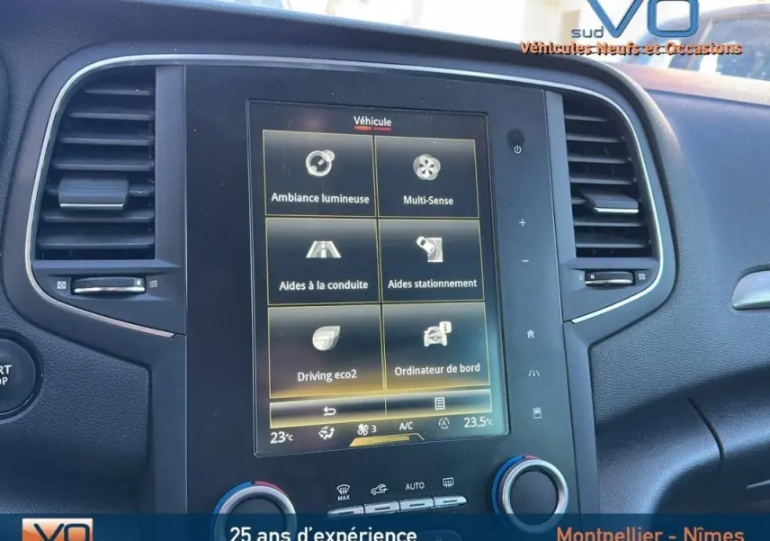 Écran tactile central de la Renault Mégane IV beige, affichant les aides à la conduite et climatisation automatique.