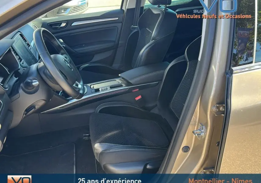 Vue intérieure côté conducteur d'une Renault Mégane IV beige de 2017, sièges noirs et tableau de bord moderne.