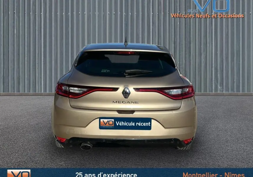 Vue arrière d'une Renault Mégane IV beige, avec feux LED et logo central bien visibles sur fond urbain.
