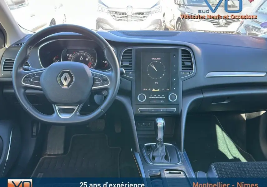 Tableau de bord et volant cuir d'une Renault Mégane IV beige, avec écran tactile et levier de boîte automatique visible.