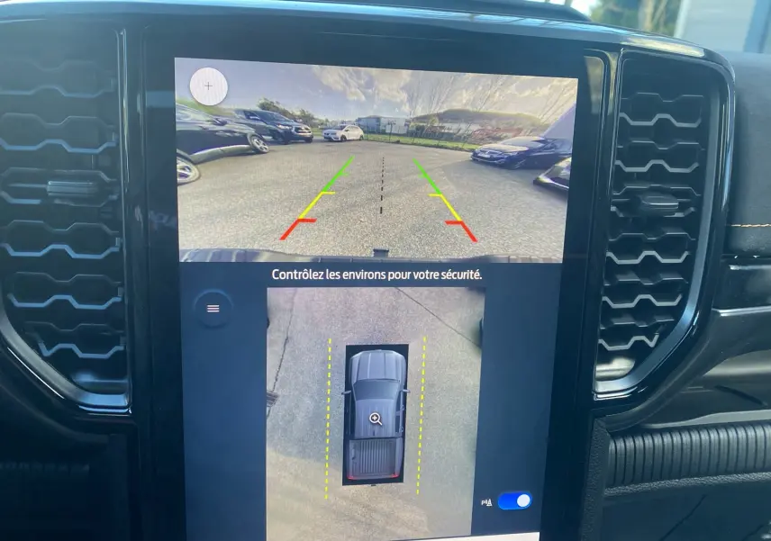 Écran central montrant la caméra 360° du Ford Ranger gris carbone, vue arrière et vue aérienne du véhicule en stationnement.