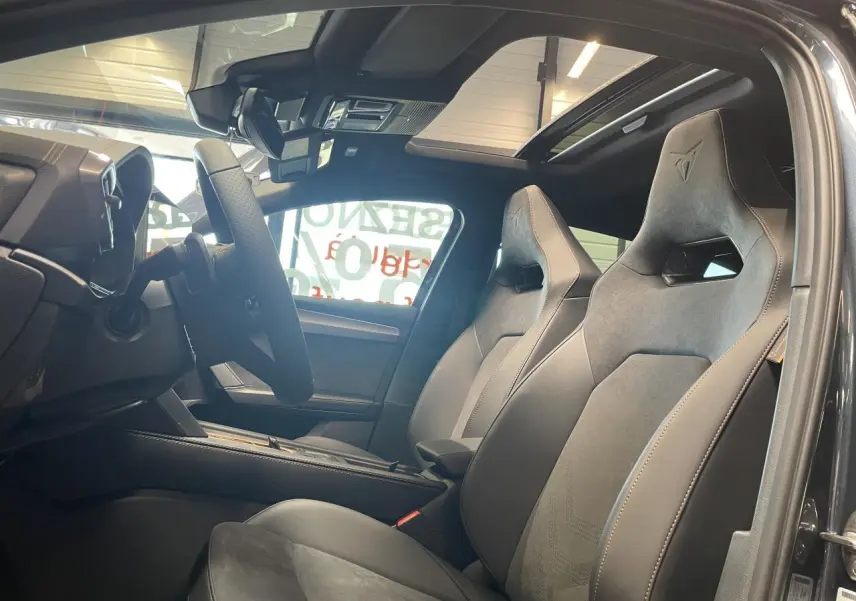 Vue intérieure côté conducteur de la CUPRA Leon 2026 gris magnetic, sièges baquets suédine noire avec surpiqûres cuivrées.
