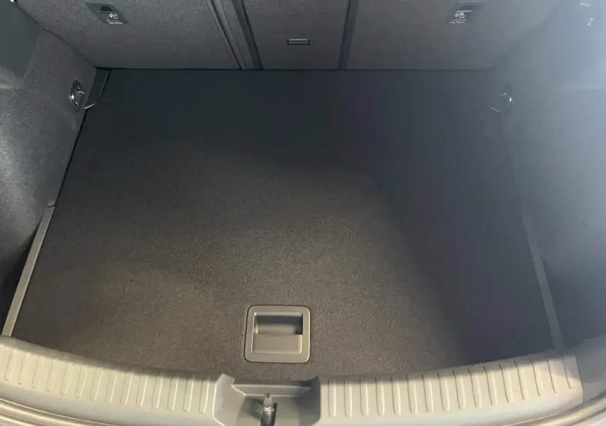 Coffre ouvert vu de dessus, intérieur noir, tapis de sol plat et poignée centrale visible.