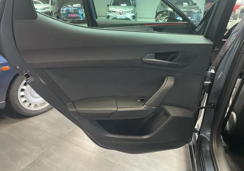 Contre-porte arrière droite de la CUPRA Leon gris magnetic, avec poignée intégrée et finition noire texturée.