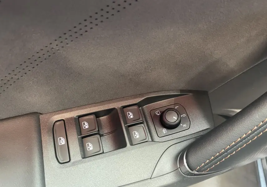 Détail des commandes de lève-vitres et réglage des rétroviseurs sur la porte côté conducteur d’une CUPRA Leon gris Magnetic.