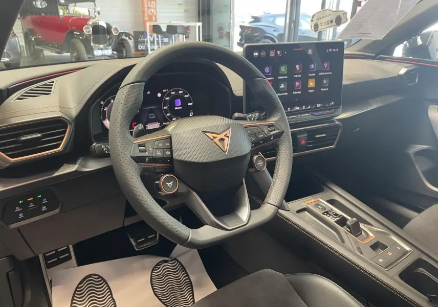 Vue intérieure du poste de conduite de la CUPRA Leon 2026, volant cuir perforé avec logo cuivré et écran tactile HD.