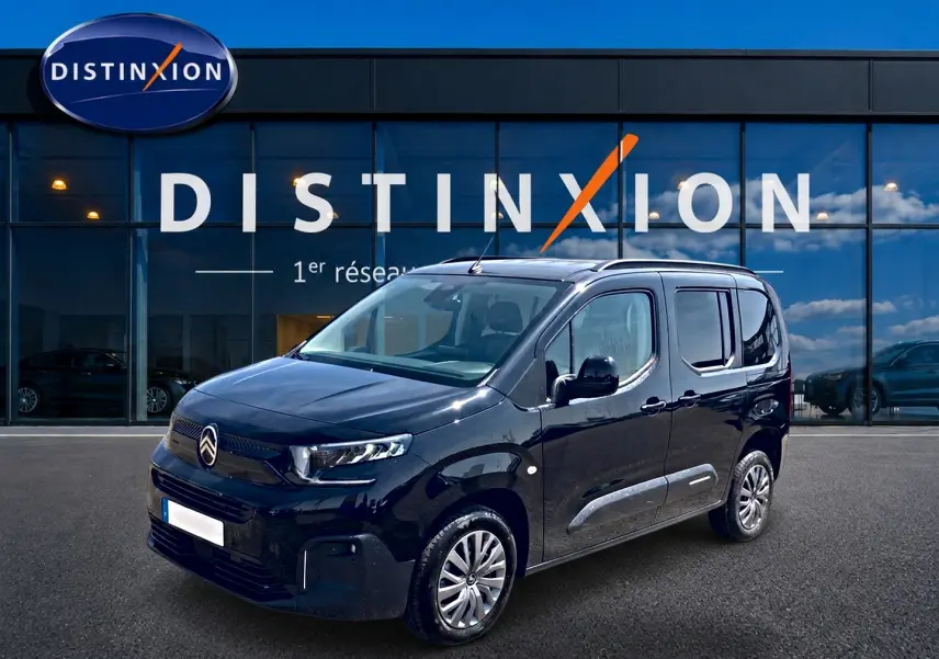 Citroën Berlingo noir vue 3/4 avant droit, avec barres de toit et jantes alu devant showroom Distinxion.