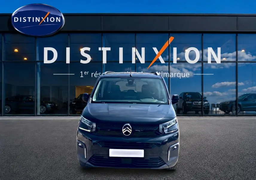 Vue avant centrée du Citroën Berlingo noir 2026 avec phares LED et logo distinctif sur fond vitré d'un showroom.