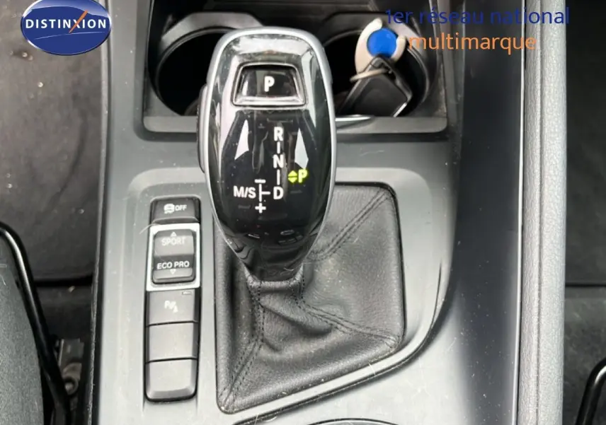 Gros plan sur le levier de vitesses automatique noir du BMW X1 18i gris argent, avec boutons mode Sport et Eco Pro visibles.