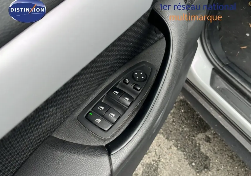 Détail des commandes des vitres sur la porte avant gauche d’un BMW X1 gris argent 2018.