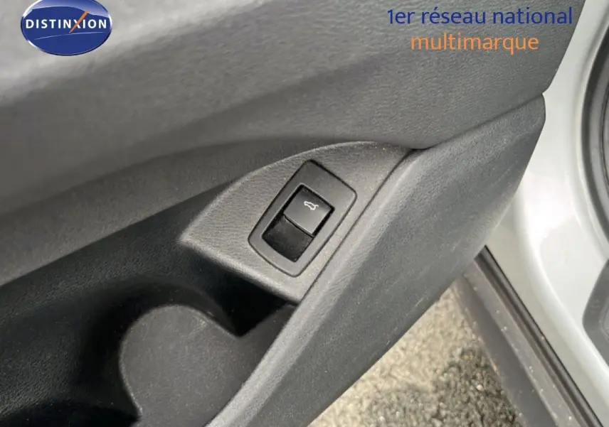 Gros plan sur le bouton d'ouverture du coffre intégré à la portière côté gauche d'une BMW X1 gris argent 2018.