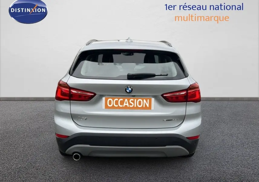 Vue arrière d'un BMW X1 gris argent métallisé, avec feux rouges et logo BMW bien visibles.