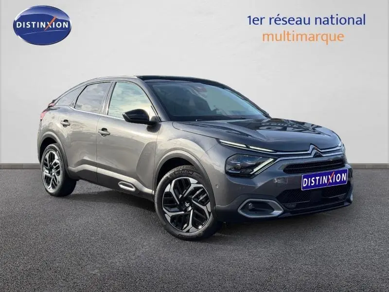 Citroën C4 gris 2024 vue 3/4 avant droit, avec jantes noires et détails lumineux distinctifs à l'avant.