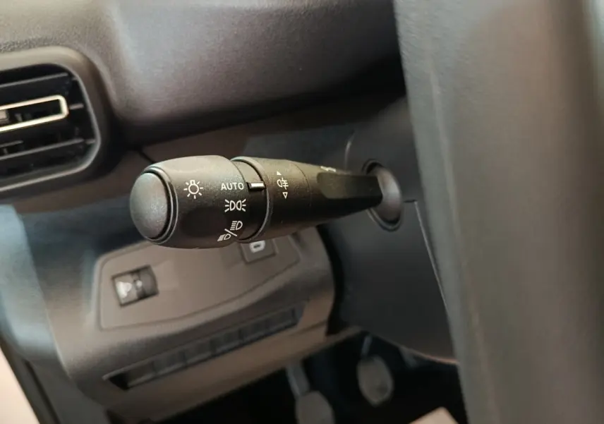 Gros plan sur la commande des phares à gauche du volant dans l’habitacle du Peugeot Partner blanc 2026.