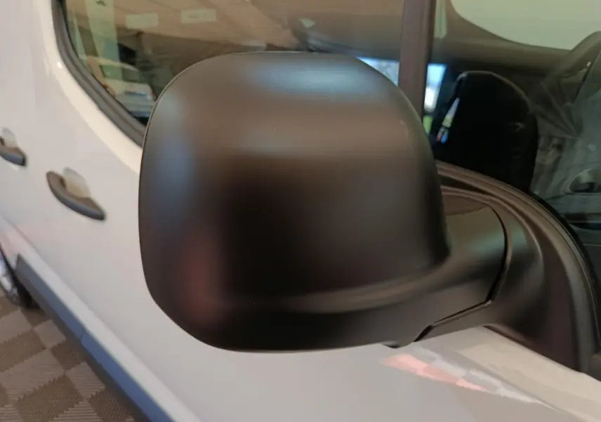 Gros plan sur le rétroviseur noir côté conducteur du Peugeot Partner blanc, vue latérale avant gauche.
