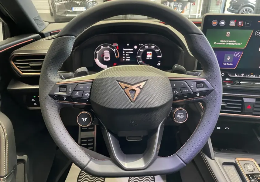 Vue rapprochée du volant noir perforé avec logo CUPRA cuivré et tableau de bord digital d'une CUPRA Leon 2026.