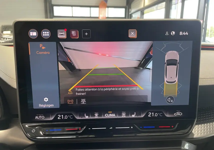 Écran tactile intérieur affichant la caméra de recul et l’aide au stationnement du CUPRA Leon noir, vue frontale du tableau de bord.