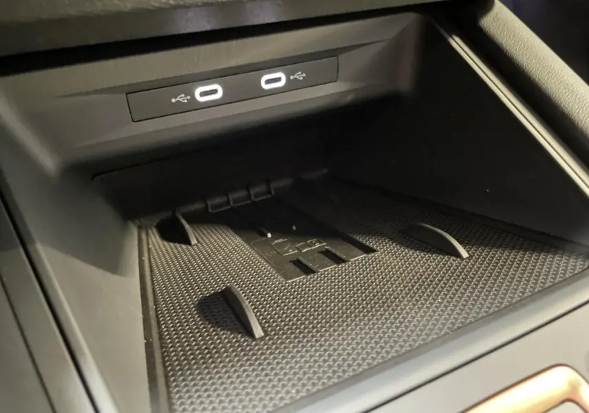 Gros plan sur la zone de recharge et ports USB-C éclairés du coffre à objets de la CUPRA Leon noire 2026.