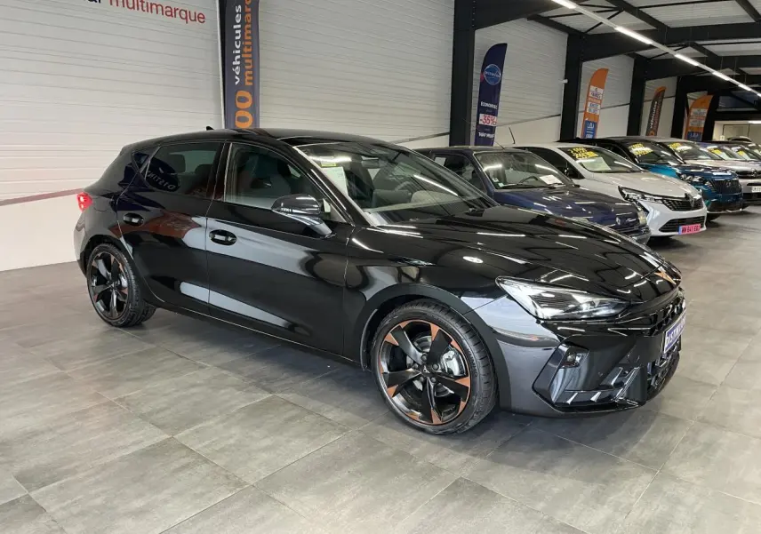 Vue 3/4 avant d'une CUPRA Leon noire avec jantes alliage 18'' cuivrées dans un showroom intérieur.