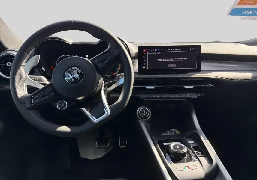 Vue intérieure du poste de conduite de l'Alfa Romeo Tonale 2025, volant cuir sport et écran tactile central visible.