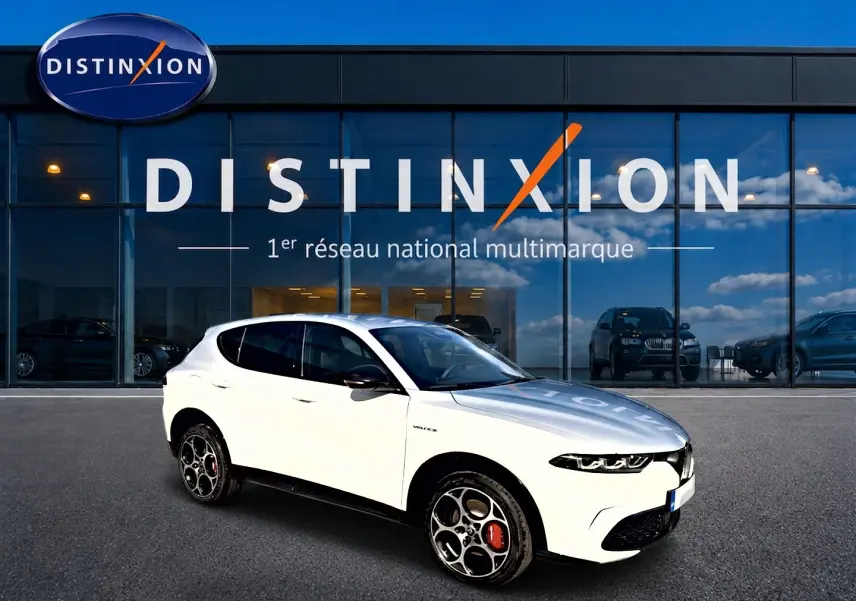 Alfa Romeo Tonale blanc en 3/4 avant droit, jantes alu distinctives et calandre noire, devant vitrine Distinxion.