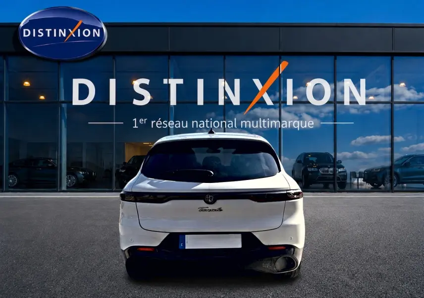 Vue arrière d'une Alfa Romeo Tonale blanche 2025 garée devant une vitrine avec logo Distinxion.