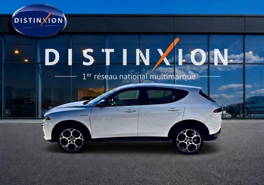 Vue de profil côté gauche d'un Alfa Romeo Tonale blanc 2025 garé devant une vitrine Distinxion.