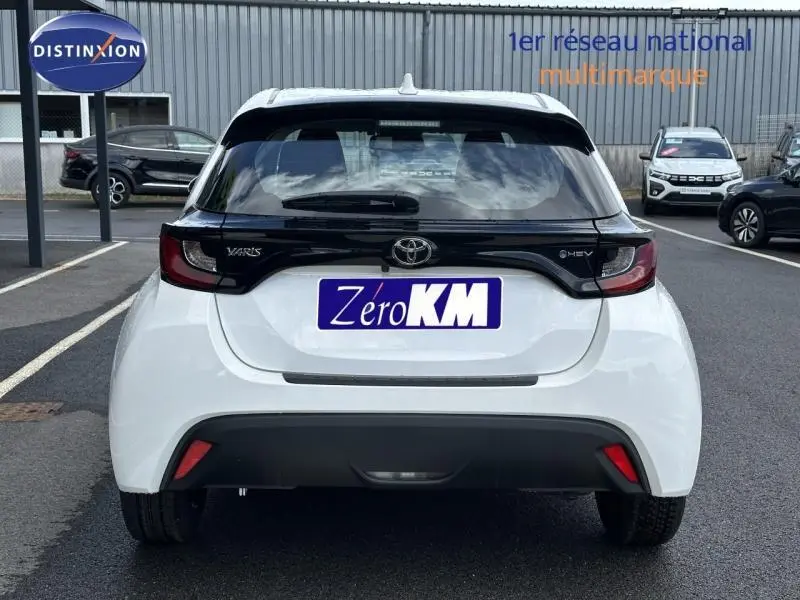 Vue arrière d'une Toyota Yaris 116h Dynamic blanche 2025 avec logo hybride et plaque Zero KM visible.