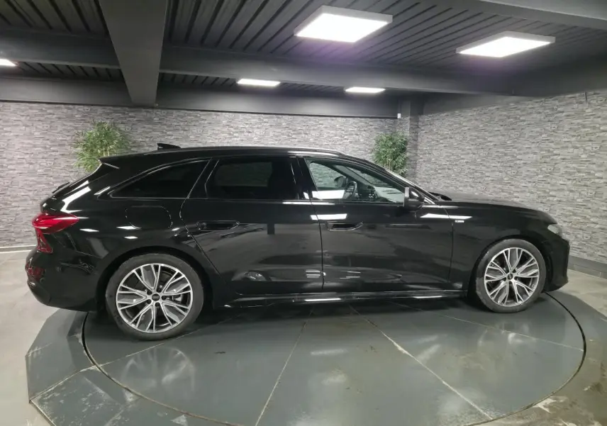 Audi A5 Avant noir vue de profil côté gauche, avec jantes 19 pouces et finitions S line visibles en intérieur urbain.