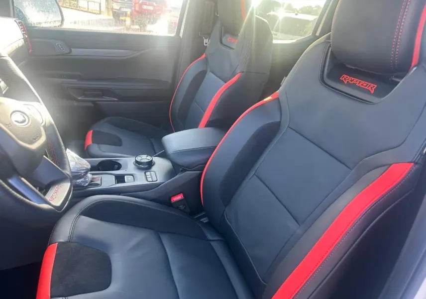 Vue intérieure côté conducteur du Ford Ranger Raptor 2025 avec sièges sport noirs et rouges brodés "Raptor".