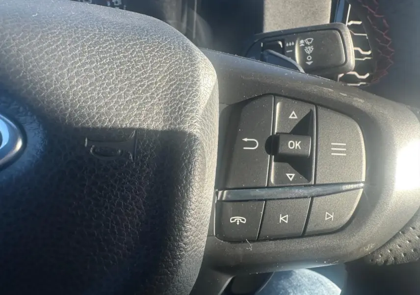 Gros plan sur les commandes multifonctions à droite du volant noir du Ford Ranger blanc 2025.