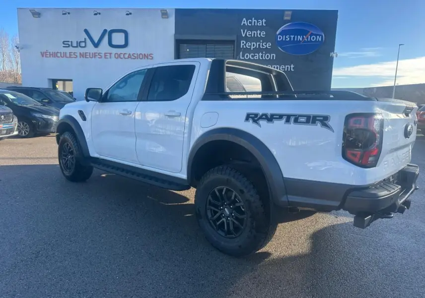 Ford Ranger Raptor blanc en vue 3/4 arrière droit, avec jantes alliage noires et marquage "Raptor" sur la caisse.