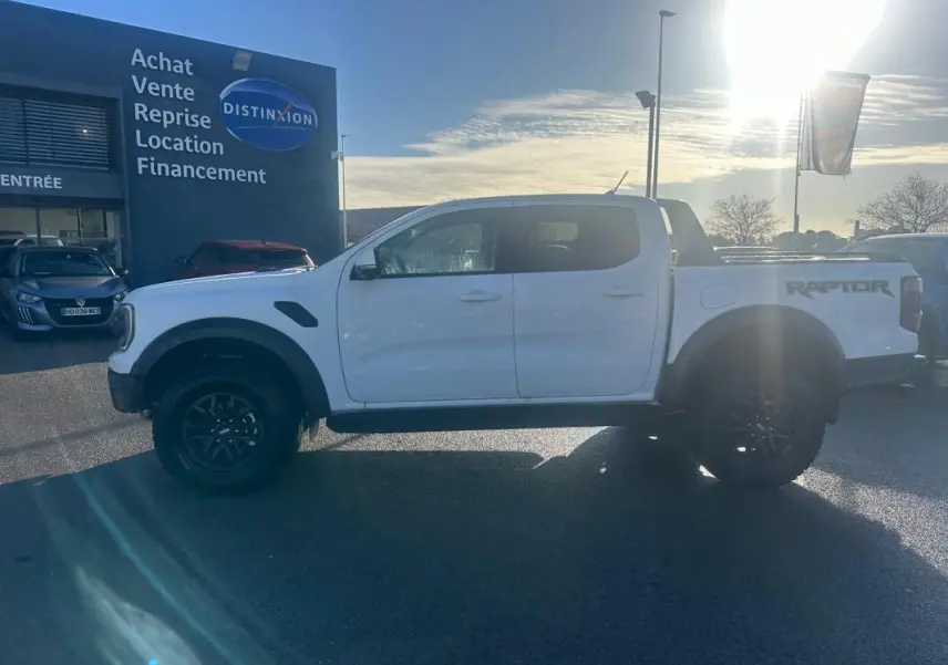 Ford Ranger Raptor blanc en profil côté gauche, avec jantes alliage noires et logo Raptor visible sur la benne.