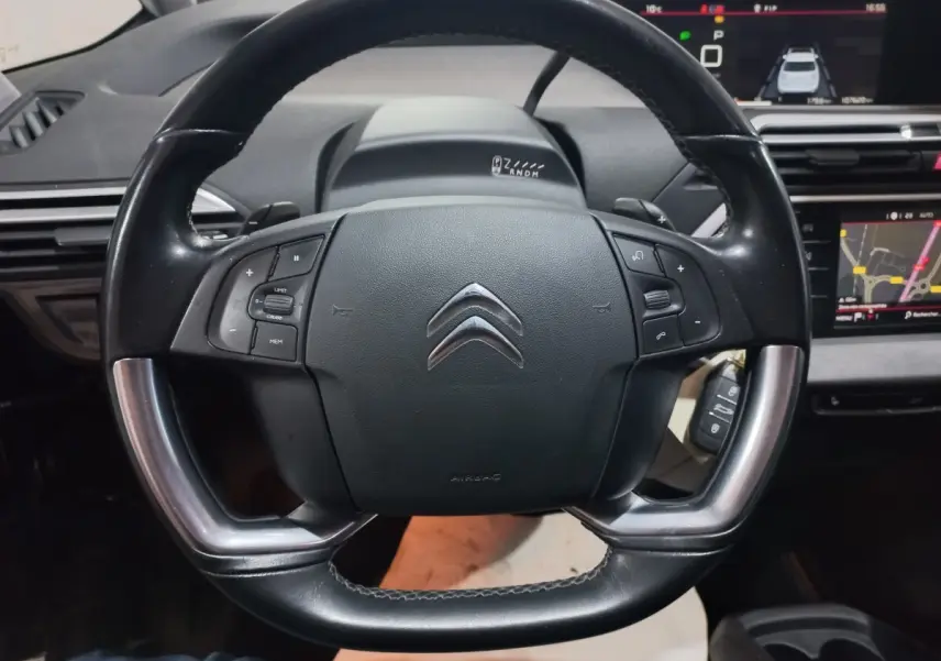 Vue rapprochée du volant cuir noir et alu du Citroën Grand C4 Spacetourer avec tableau de bord et écrans tactiles visibles.