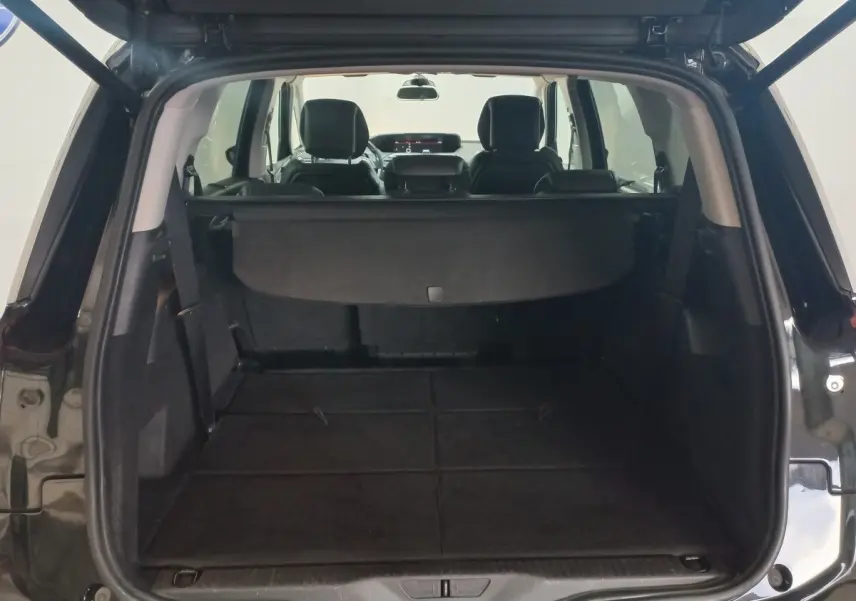 Coffre ouvert vu de l'arrière d'un Citroën Grand C4 Spacetourer noir avec banquette arrière rabattue et cache-bagages déployé.