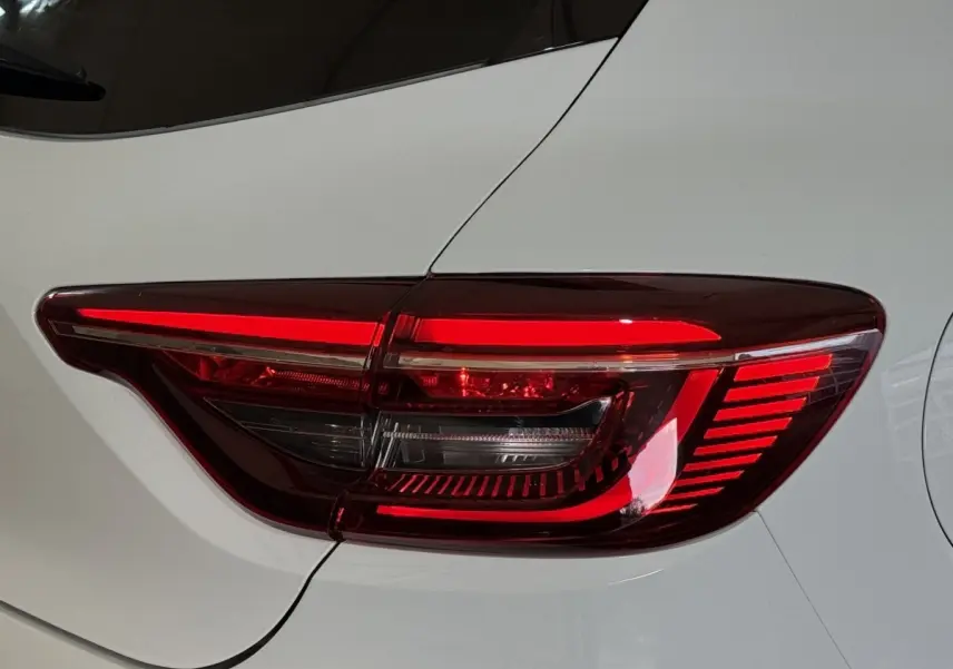 Gros plan sur le feu arrière droit rouge et blanc d'une Renault Clio Business blanche, vue de profil arrière.