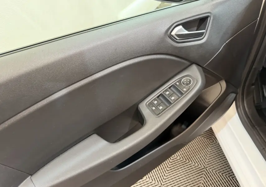 Vue intérieure côté gauche de la porte avant d'une Renault Clio blanche, avec commandes électriques des vitres et poignée intégrée.