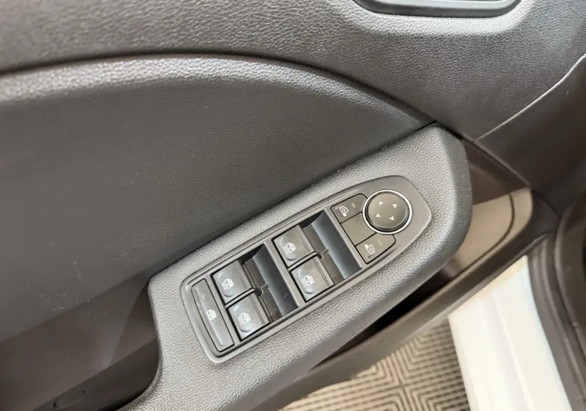 Gros plan sur les commandes des vitres électriques côté conducteur d’une Renault Clio blanche, intérieur noir.