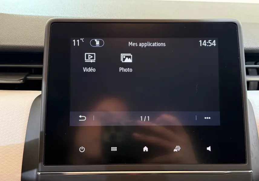 Écran tactile central de la Renault Clio Business blanc, affichant le menu des applications avec température et heure.