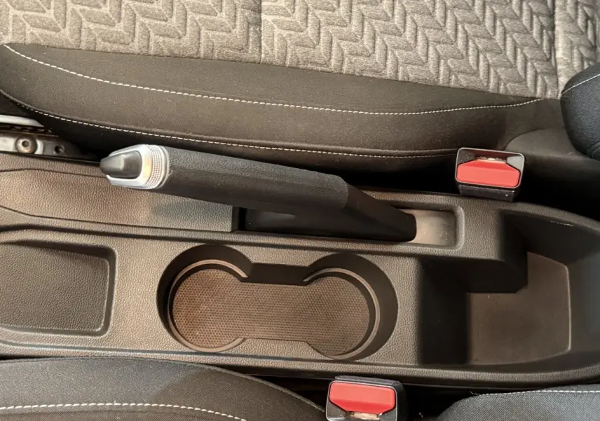 Vue rapprochée de la console centrale intérieure de la Renault Clio Business TCe 100 GPL 2022, avec frein à main manuel et porte-gobelets.