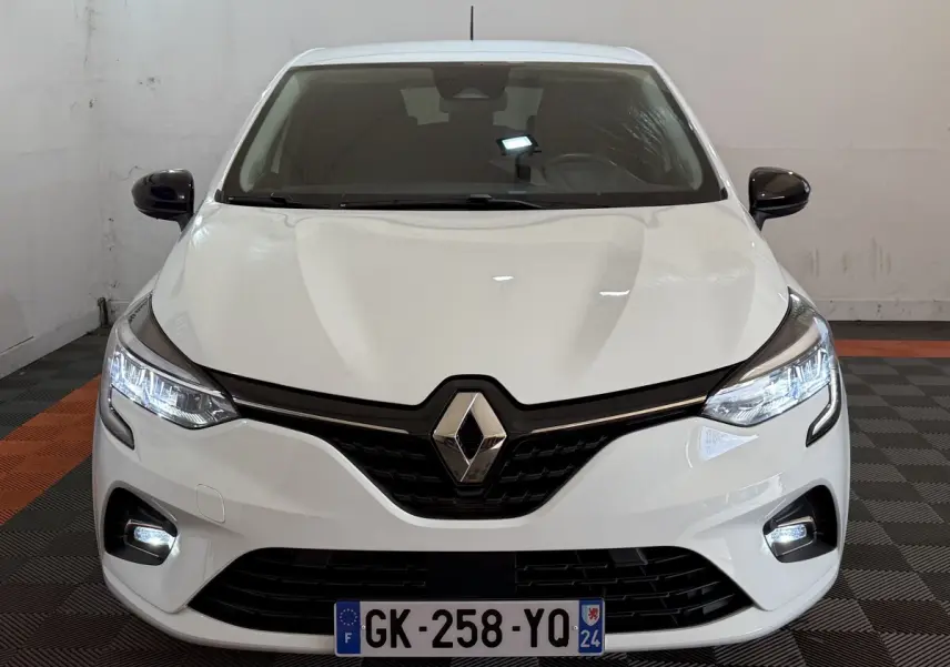 Vue frontale d'une Renault Clio Business blanche avec feux LED allumés et calandre noire brillante.