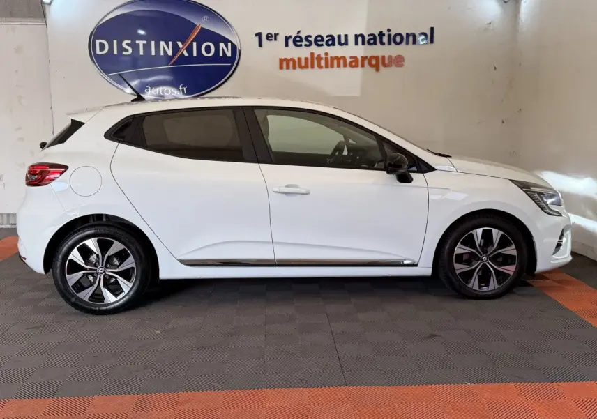 Profil droit d'une Renault Clio Business TCe 100 GPL blanche, avec jantes alliage et vitres teintées, en intérieur showroom.