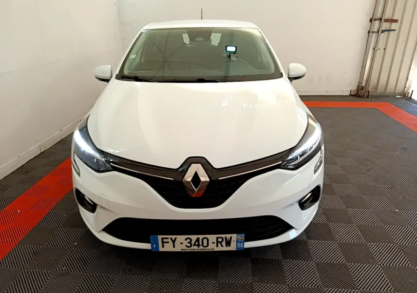 Vue de face d'une Renault Clio Business blanche 2021 avec phares LED allumés dans un garage.
