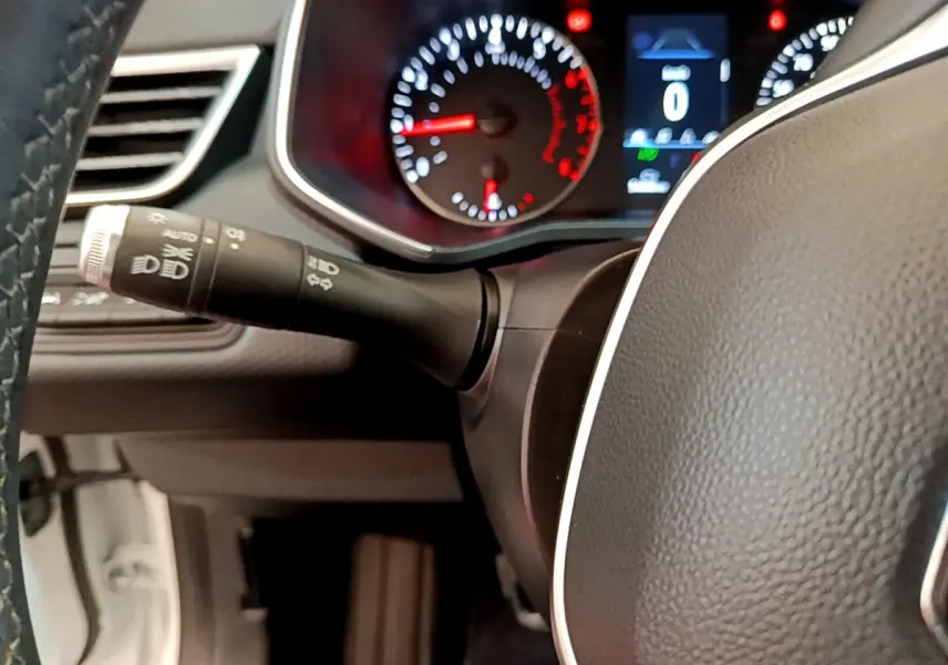 Gros plan sur le volant noir et le combiné d'instruments éclairé d'une Renault Clio Business blanche de 2021.