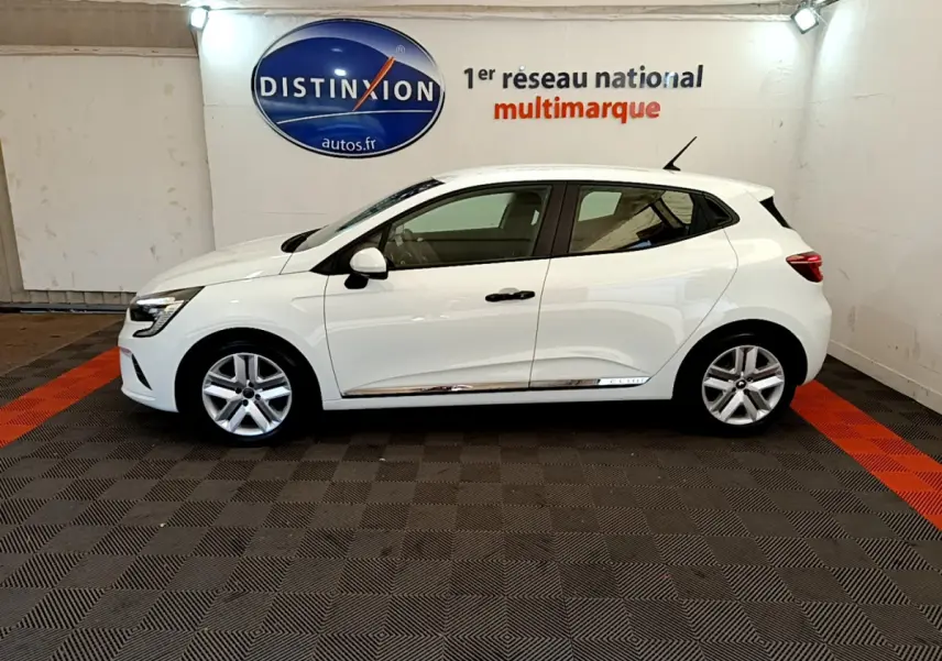 Profil côté gauche d'une Renault Clio Business blanche 2021 avec jantes alliage et poignées noires dans un showroom.