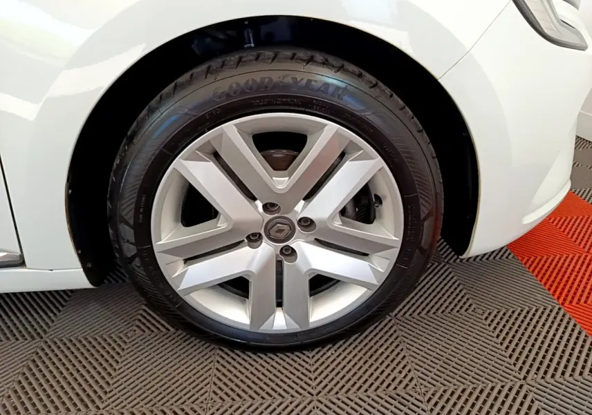 Gros plan sur la roue avant droite de la Renault Clio Business blanche, mettant en valeur la jante alliage et le pneu Goodyear.