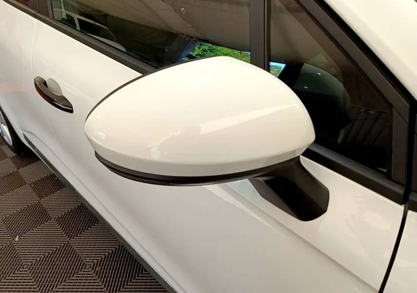 Rétroviseur droit blanc de la Renault Clio Business 2021, avec poignée de porte assortie visible en arrière-plan.