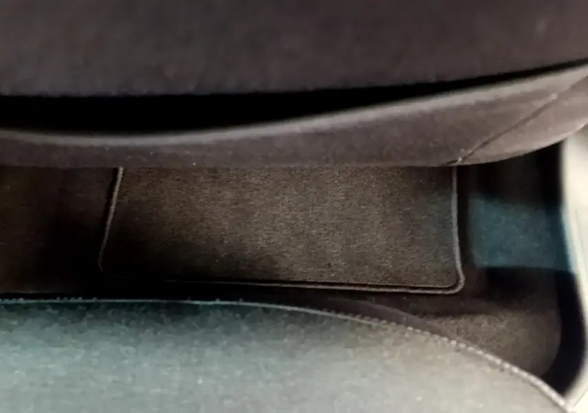 Gros plan sur le tapis de sol noir côté passager de la Renault Clio Business blanche, intérieur épuré.