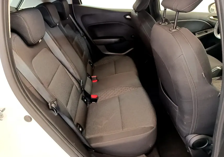 Vue intérieure côté gauche sur les sièges arrière noirs de la Renault Clio Business blanche, avec ceintures et appuie-têtes visibles.