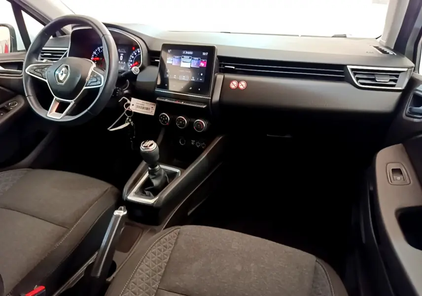 Vue intérieure avant droite de la Renault Clio Business blanche 2021 avec tableau de bord tactile et boîte manuelle.